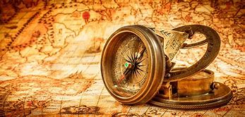 Old-fashioned compass and rolled parchment map placed on a wooden surface, symbolising exploration and discovery in History studies.