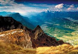 Scenic landscape with mountains, green valleys, and a bright blue sky, representing the study of Geography and exploration of the natural world.
