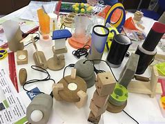 Table filled with creative design projects, including cardboard models, colourful paper, and crafting tools, representing Design and Technology activities.